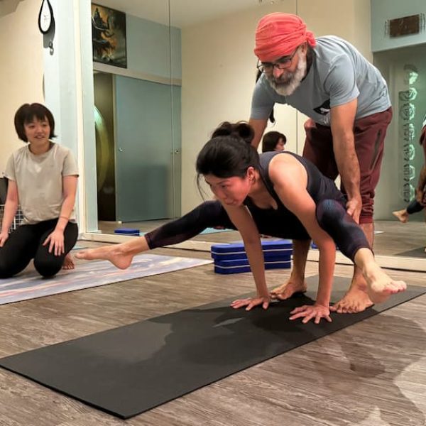Teacher Supporting A Student With Arm Balancing Yoga In Singapore